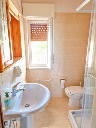 a bathroom with a sink and a toilet and a window at Wanderlust Sicily Mongiove in Mongiove