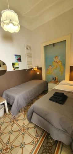 um quarto com duas camas e um quadro na parede em Affittacamere Museo em Taranto
