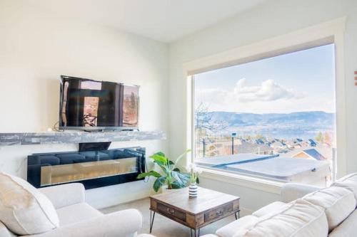 a living room with a fireplace and a large window at Lakeview 2-bed 2-bath Entire Suite near Summerhill Winery in Kelowna
