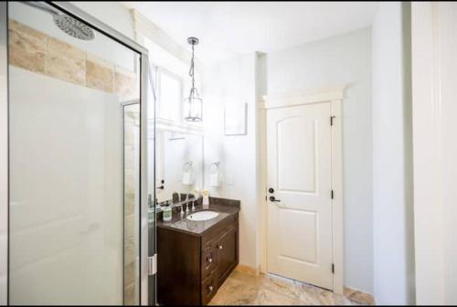 a bathroom with a sink and a shower with a mirror at Lakeview 2-bed 2-bath Entire Suite near Summerhill Winery in Kelowna