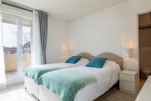 une chambre blanche avec deux lits et une fenêtre dans l'établissement RARE! 120m ROOFTOP 5-minute walk to downtown, à Cannes