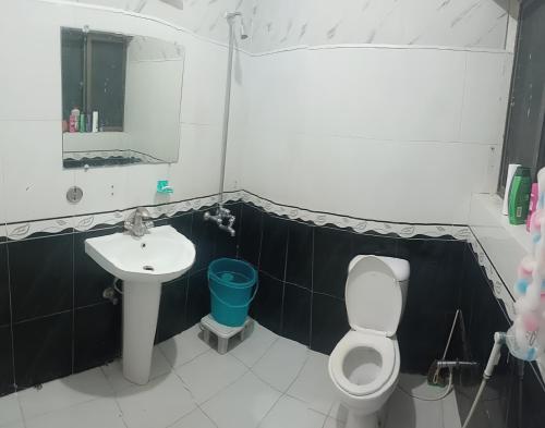 a bathroom with a white toilet and a sink at Al Sadiq Guest House in Murree