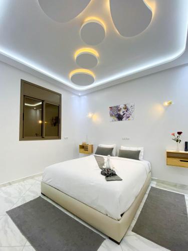 a bedroom with a large white bed with a ceiling at Hotel apartment america in Dakhla