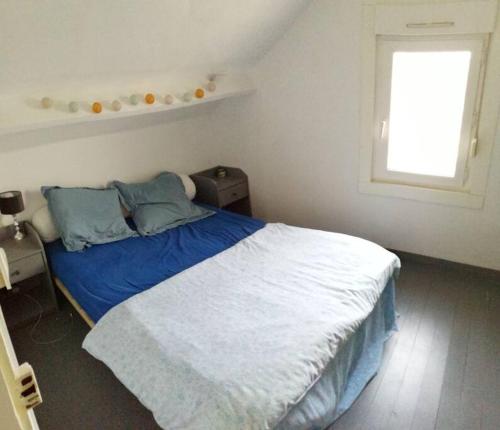 une chambre avec un lit avec des oreillers bleus et une fenêtre dans l'établissement Jolie Duplex à deux pas de la plage, à Berck-sur-Mer