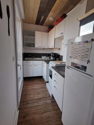 een keuken met witte kasten en een houten vloer bij Jolie Duplex à deux pas de la plage in Berck-sur-Mer