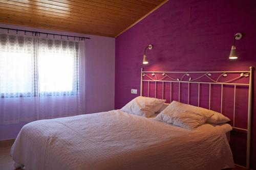 a bedroom with a bed with purple walls and a window at CASA RURAL EL PINICO in Yeste