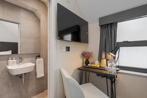 een badkamer met een wastafel en een bureau met een wastafel bij King's Cross Express Inn in Londen