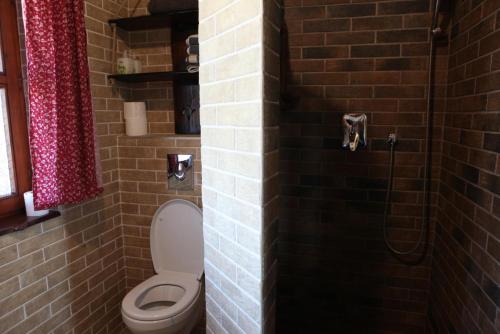 a bathroom with a toilet and a brick wall at Bakonyszentkirályi Menedék in Bakonyszentkirály