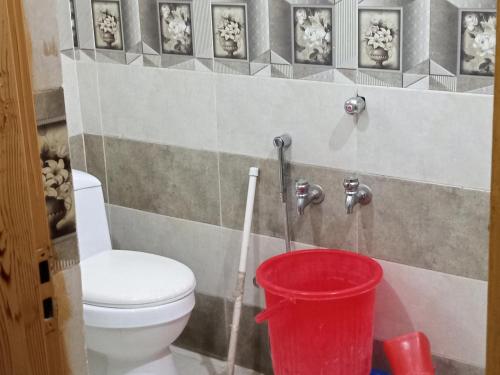 a bathroom with a toilet and a red bucket at Al Sadiq Guest House in Murree