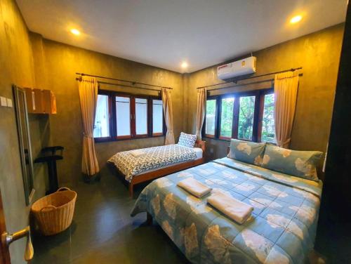 a bedroom with a large bed and two windows at Ban Chomchan Pool Villa Khaoyai in Ban Tha Chang
