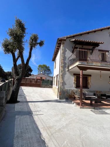 a building with a tree next to a sidewalk at Casa Rural El Pinaron in Navaluenga