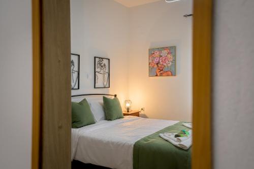 a bedroom with a bed with green pillows and a mirror at Delfini Bliss 1 in Alexandroupoli