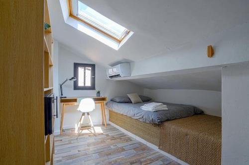 une chambre avec un lit, un bureau et une fenêtre dans l'établissement Studio sous les toits très bien placé et climatisé, à Montpellier