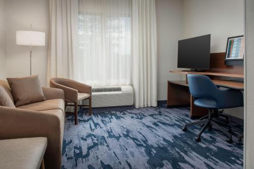 a hotel room with a couch and a desk and a television at Fairfield Inn & Suites by Marriott Ithaca in Ithaca