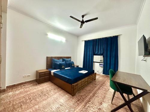 a bedroom with a blue bed and a table at Entire flr 2BHK+terrace near Medanta hospital ggn in Gurgaon