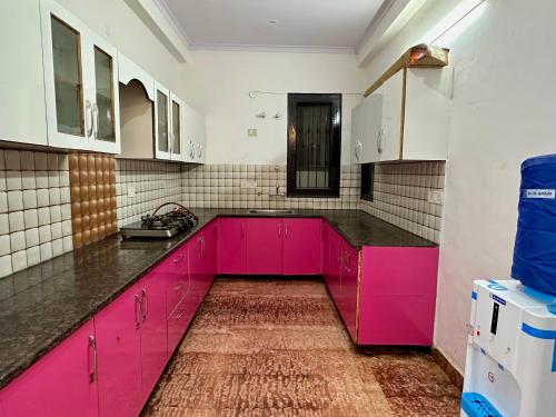 a kitchen with pink cabinets and black counter tops at Entire flr 2BHK+terrace near Medanta hospital ggn in Gurgaon