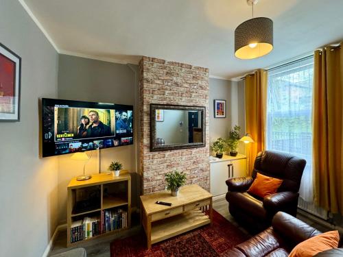 a living room with a couch and a tv on a brick fireplace at Waterloo House - Great for Contractors or Family Holidays in Nottingham