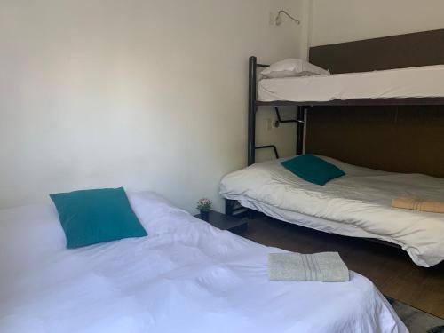 2 beliches num quarto com lençóis brancos e almofadas azuis em Hermosa Habitación con balcon cama mat y litera Polanco em Cidade do México