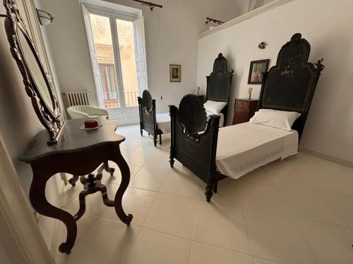 a bedroom with two beds and a table and a mirror at Palazzo Quey in Lecce