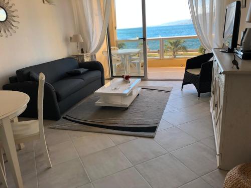 een woonkamer met een bank en uitzicht op de oceaan bij Grand F1 face à la plage, Climatisé, parking, grand confort 4 pers in Propriano