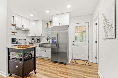 a kitchen with white cabinets and a stainless steel refrigerator at Midtown CharmMinutes to Downtown, FSU, FAMU in Tallahassee