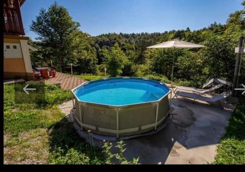 a large swimming pool in a yard with an umbrella at Planinaki Raj in Lokve