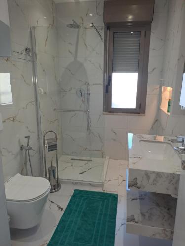 a white bathroom with a toilet and a sink at Erdis Home Nr 1 in Tirana