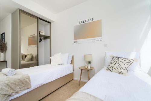 - une chambre avec 2 lits et un miroir dans l'établissement Brightway Hemel, WiFi and Netflix, Perfect for Contractors and Relocators, à Hemel Hempstead