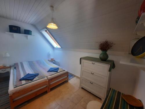 um pequeno quarto com uma cama, uma cómoda e uma janela em Tánczos Pince Vendégház em Zánka