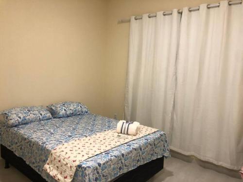 a bedroom with a bed and a window with curtains at Belíssima casa no condomínio Mar Doce de Abrolhos in Caravellas