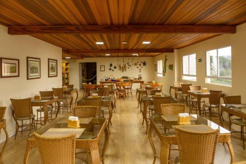 um restaurante com tectos e mesas e cadeiras de madeira em Pousada Kaliman Premium em Campos do Jordão