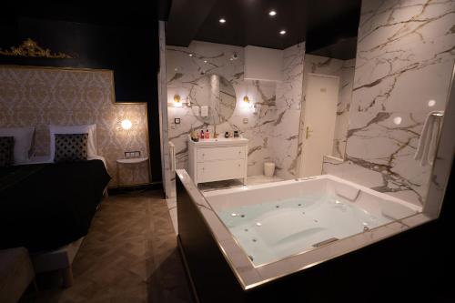 Habitación con baño blanco grande con bañera. en Appartement d'exception avec Jacuzzi, en Villefranche-sur-Saône