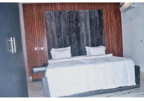 a bedroom with a white bed with a wooden headboard at Empire Suites And Apartment in Abuja