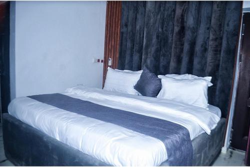 1 cama grande con sábanas y almohadas blancas en Empire Suites And Apartment, en Abuja