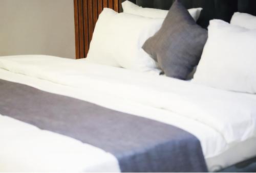 two beds with white sheets and a gray pillow at Empire Suites And Apartment in Abuja