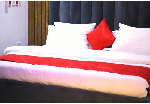 a bed with red and white pillows on it at Empire Suites And Apartment in Abuja