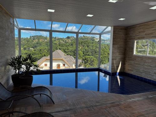 een grote kamer met een zwembad en een groot raam bij Pousada Kaliman Premium in Campos do Jordão