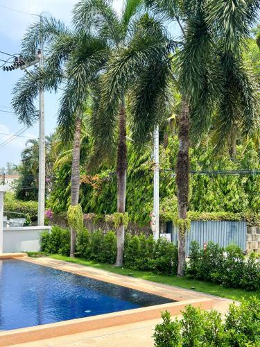 a swimming pool with palm trees in a yard at Botanic Boutique Hotel Surin Beach in Bang Tao Beach