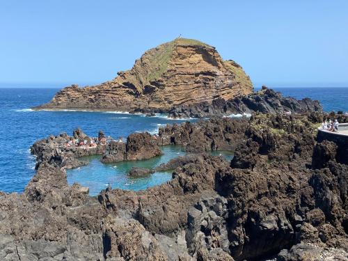 a group of people standing on a rocky island in the ocean at Ocean Garden, 4 units by the ocean in São Vicente