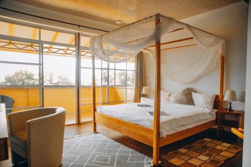 een slaapkamer met een hemelbed en een stoel bij Edelwyss-Inn in Morogoro