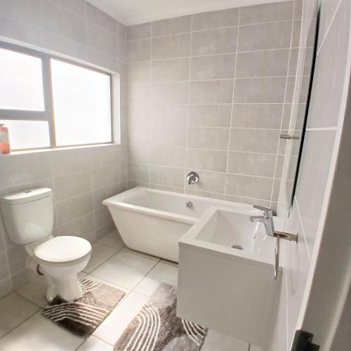 een badkamer met een bad, een toilet en een wastafel bij The Luxe Marvelous Apartment in Pretoria