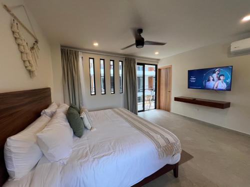 um quarto com uma grande cama branca e uma televisão de ecrã plano em New Studio p/2, jacuzzi, alberca, roof top em Tulum