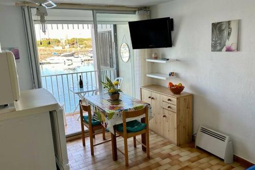 eine Küche mit einem Tisch, einem Tisch und einem Fenster in der Unterkunft Appartement ensoleillé au Cap d'Agde in Cap d'Agde