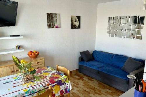 ein Wohnzimmer mit einem blauen Sofa und einem Tisch in der Unterkunft Appartement ensoleillé au Cap d'Agde in Cap d'Agde