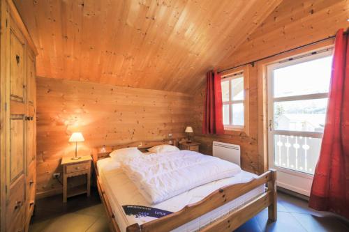 - une chambre avec un lit dans une pièce en bois dotée d'une fenêtre dans l'établissement Les Chalets de Flaine Hameau - maeva Home - Chalet 7 Pièces 12 Personnes - Prestige MAE-3379, à Flaine