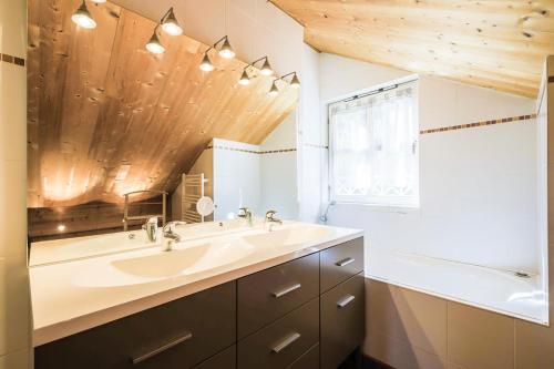 une salle de bain avec un lavabo, une baignoire et un miroir dans l'établissement Les Chalets de Flaine Hameau - maeva Home - Chalet 7 Pièces 12 Personnes - Prestige MAE-3379, à Flaine