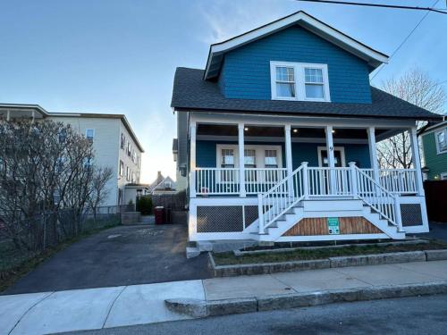 a blue house with a white porch and a driveway at Home Away From Home in Lowell in Lowell