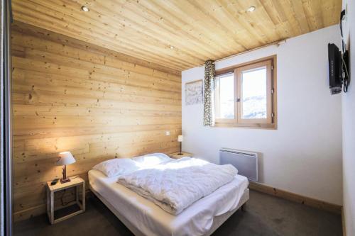 - une chambre avec un grand lit dans un mur en bois dans l'établissement Résidence Refuge du Golf - maeva Home - Appartement 2 pièces 4 personnes Prestige MAE-3482, à Arâches-la-Frasse