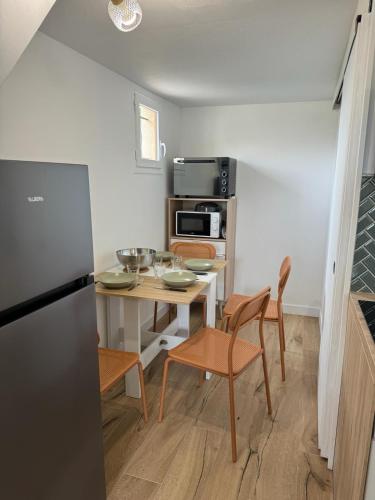 Il comprend une petite cuisine avec une table, des chaises et un réfrigérateur. dans l'établissement Maisonnette Au bord du lac Marin Port Leucate, à Leucate