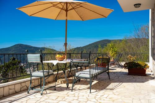a patio with a table and chairs and an umbrella at Ventus Rosa Villa in Budva